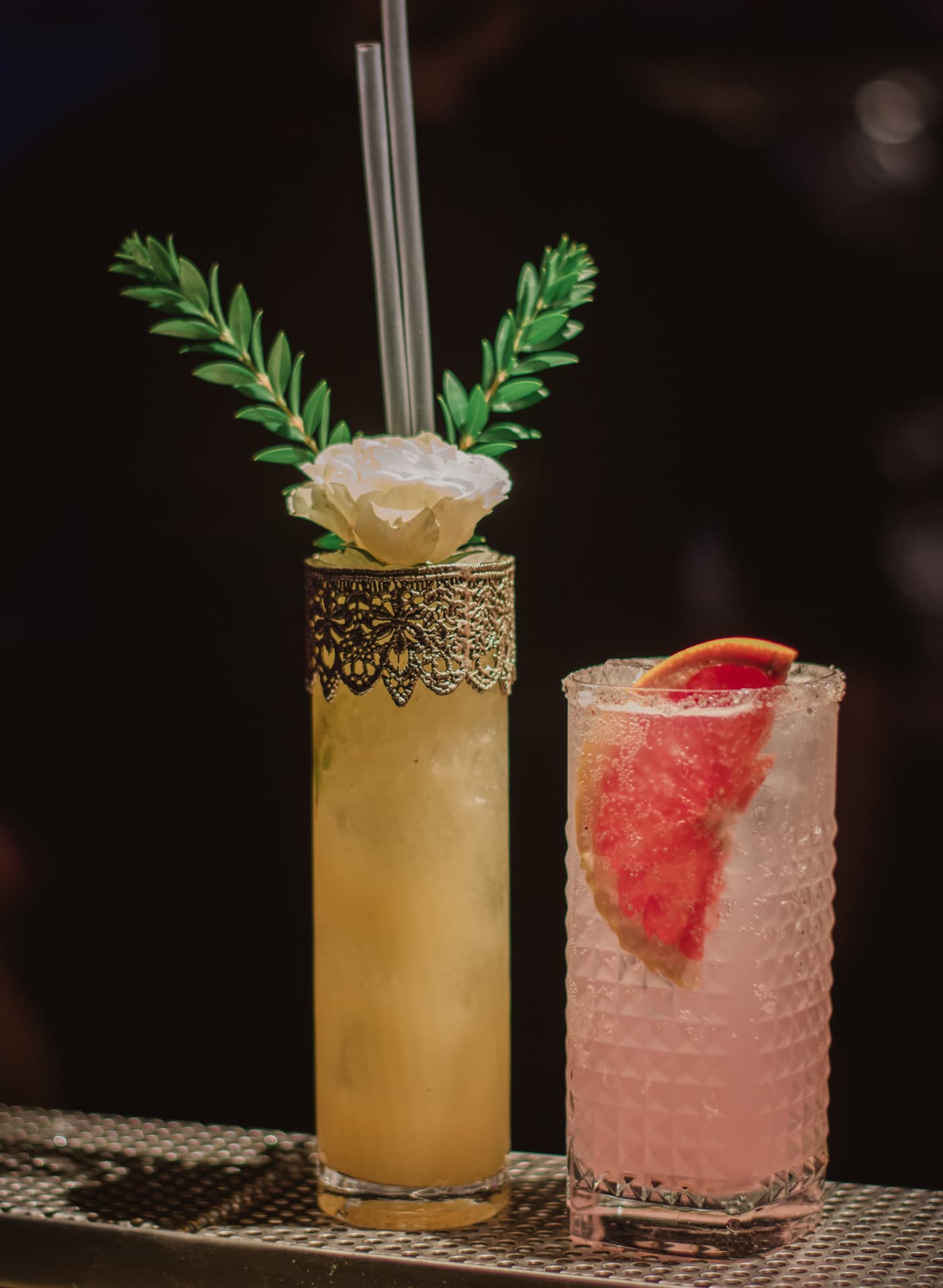 Tall lace-collared cocktail with a white rose beside a grapefruit highball