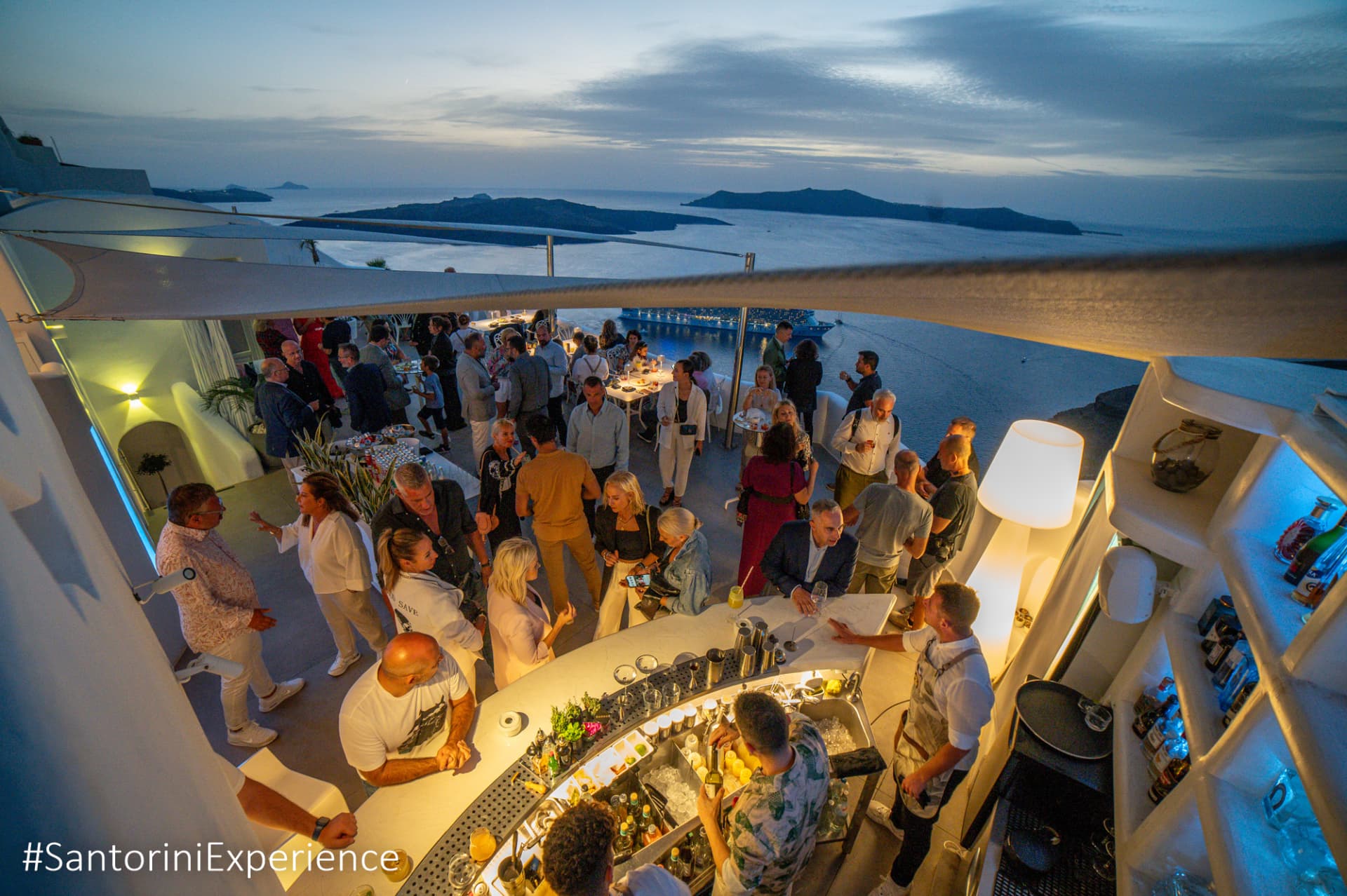 Guests around the Esperisma bar at dusk overlooking the Santorini caldera
