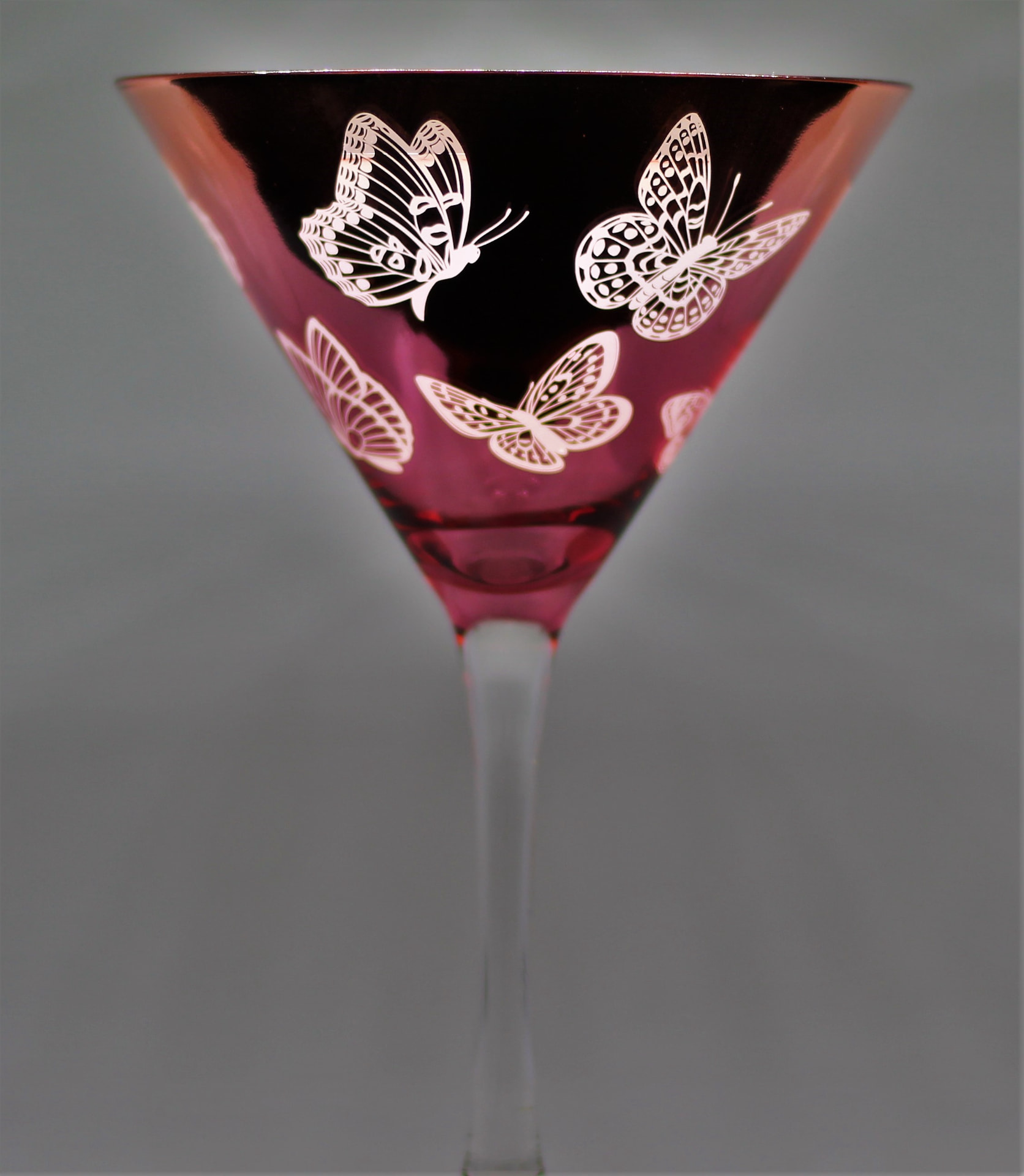 Butterfly-etched crimson martini glass photographed as a still life