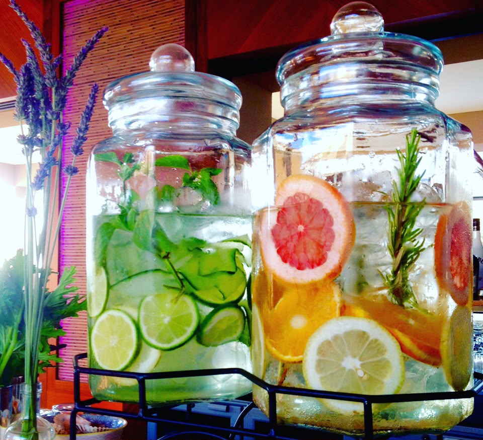 Two glass infusion jars with citrus, cucumber, mint and rosemary
