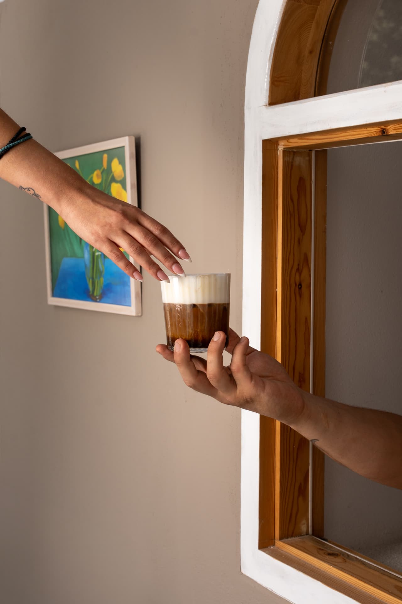 Iced coffee passed from hand to hand through an arched window