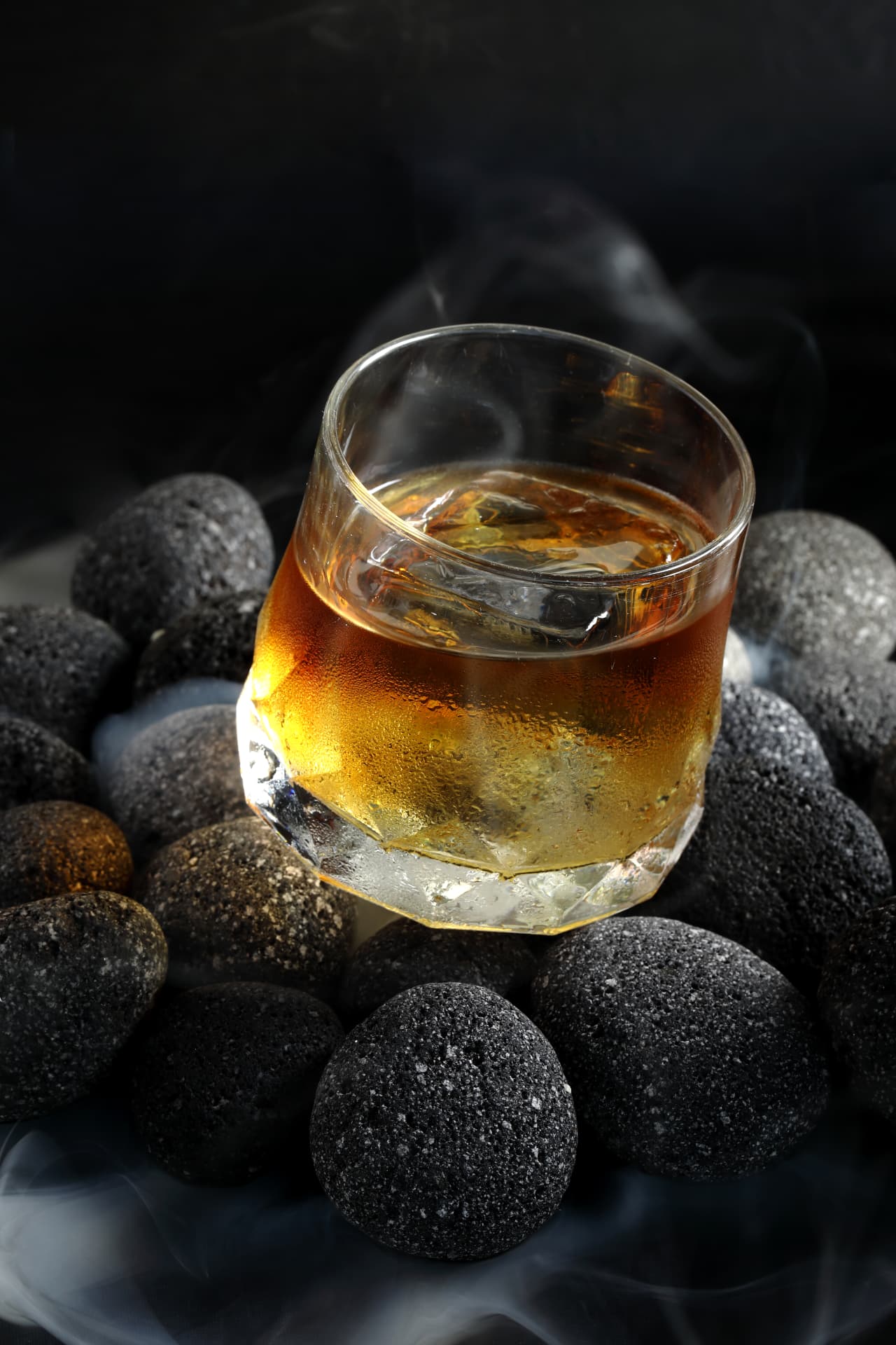 Smoked amber serve resting on black volcanic pebbles