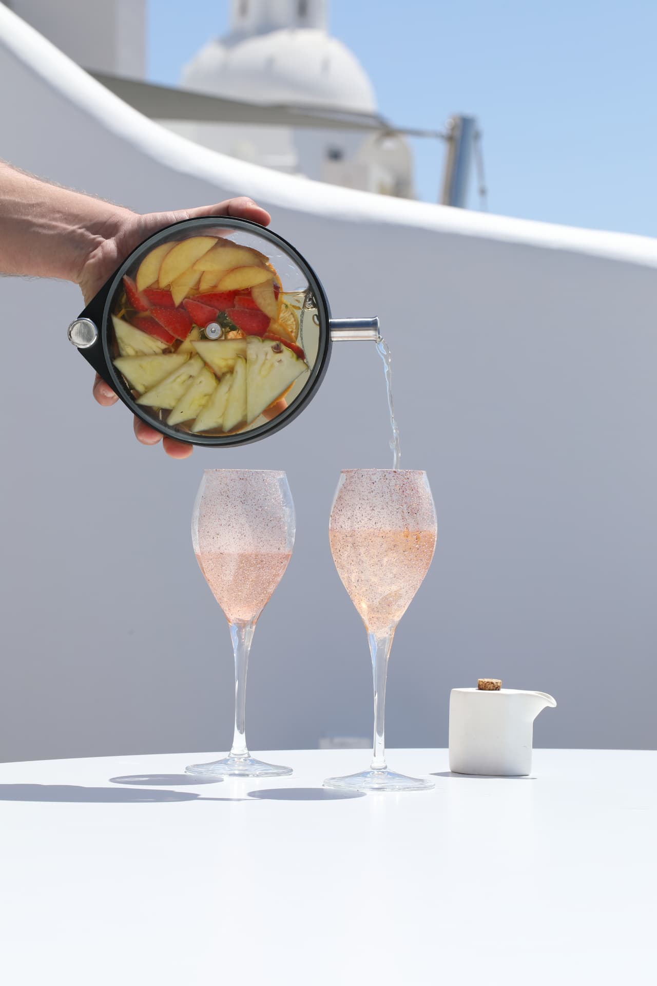 Sangria-style punch poured into two sugar-rimmed flutes on a Santorini terrace