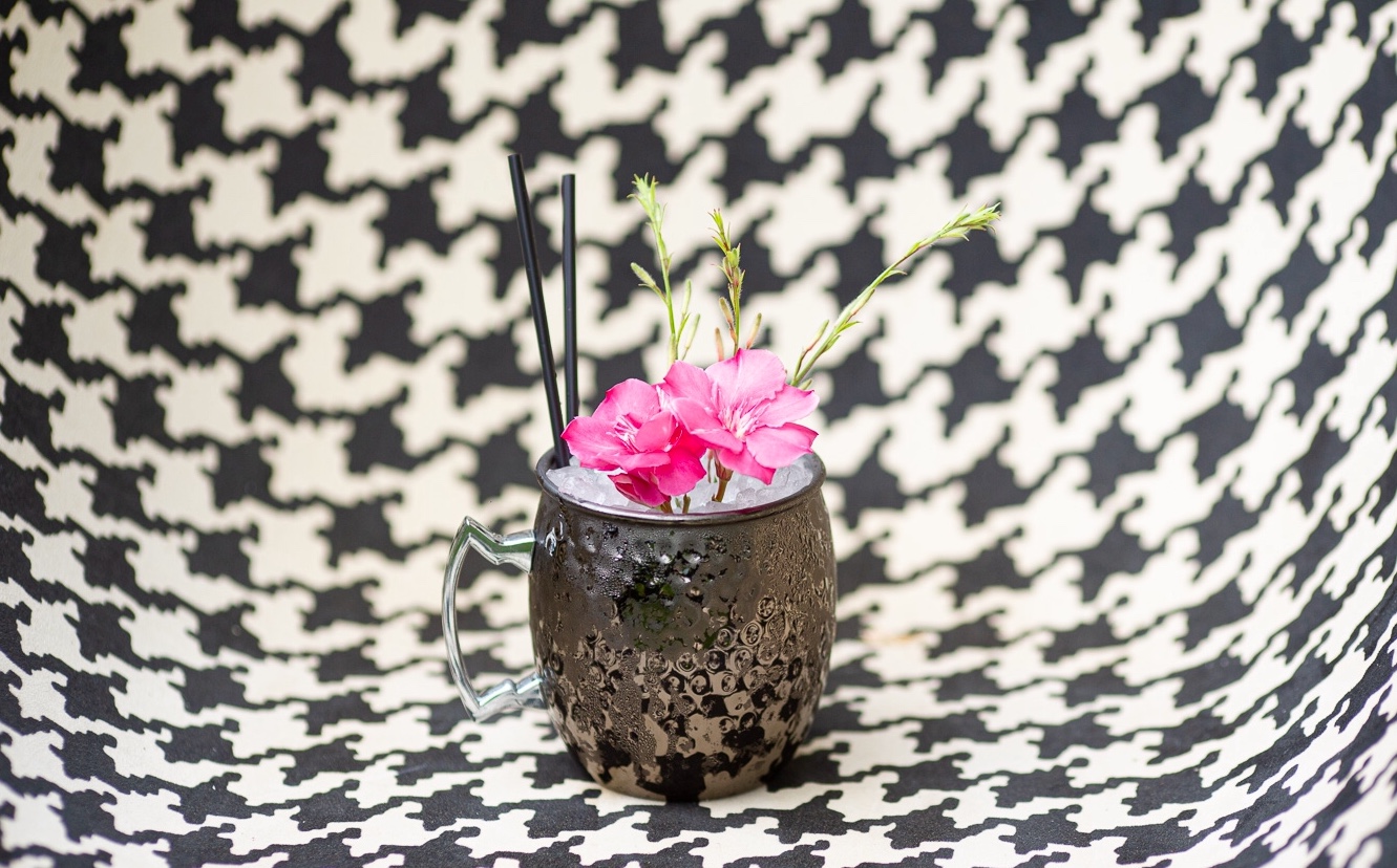 Black mule mug with crushed ice and pink oleander against houndstooth