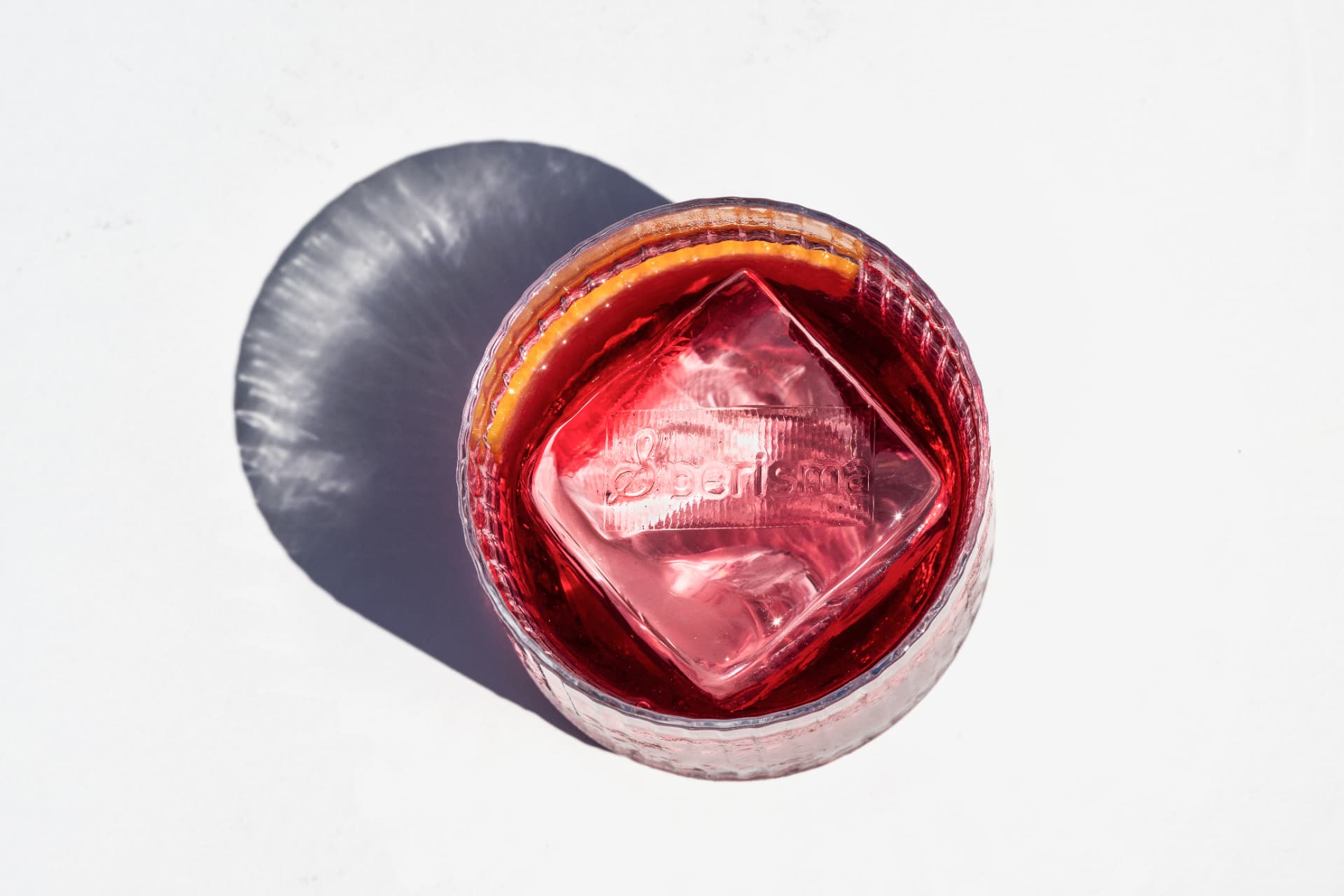 Top-down negroni with a branded clear ice cube and orange peel