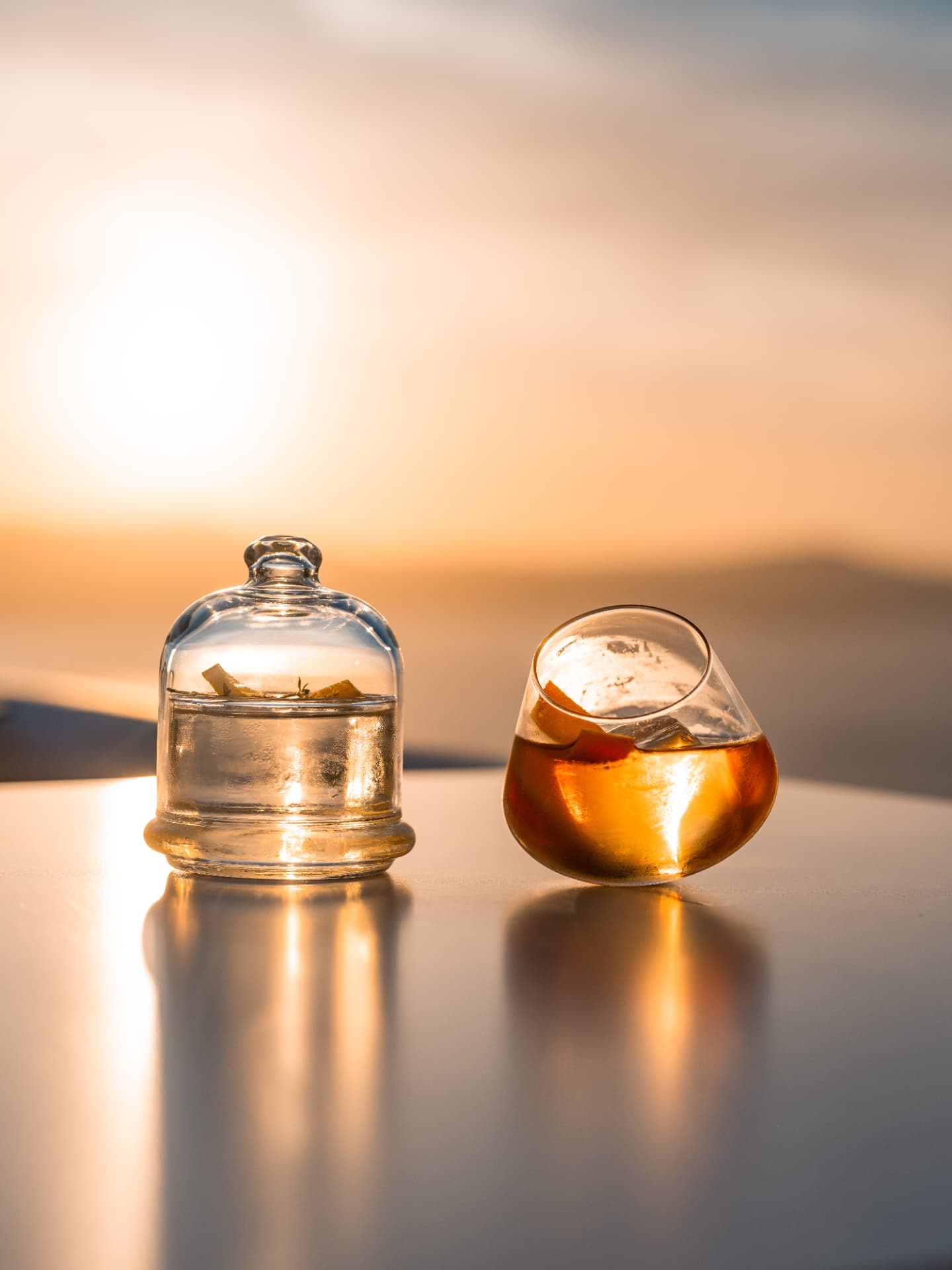 Two-part sunset serve with a cloche and tilted rocks glass