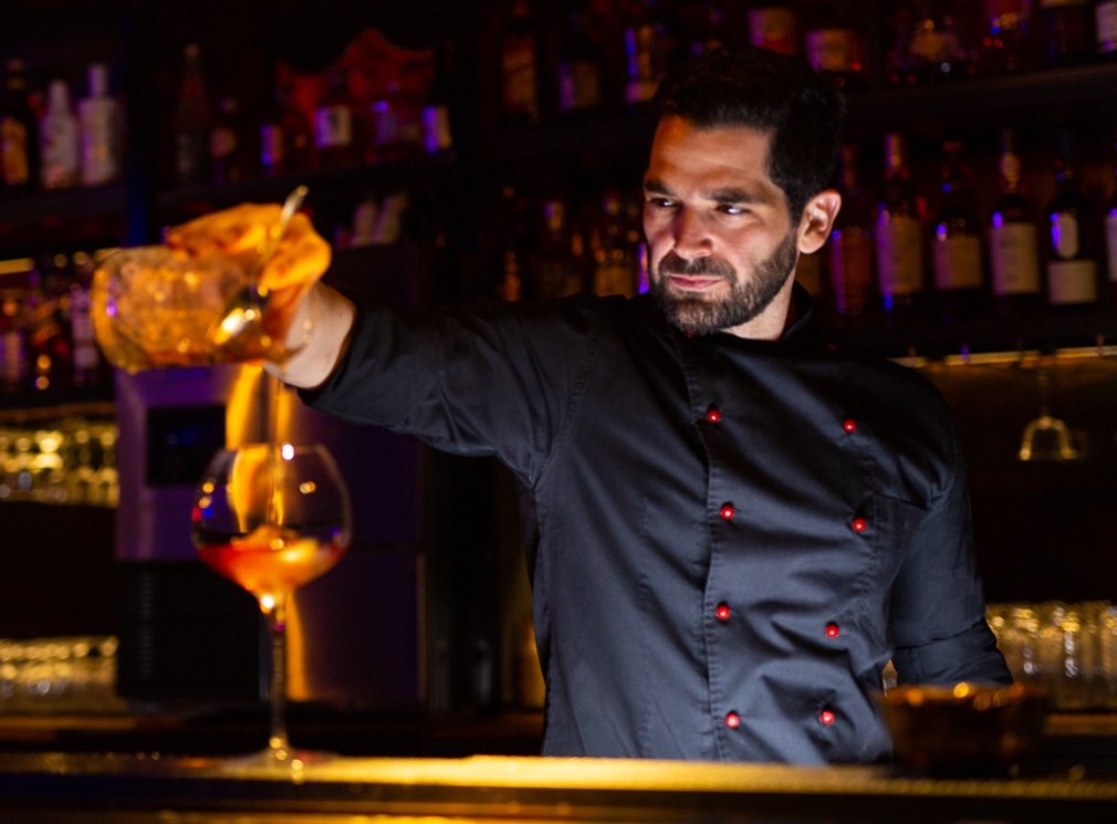 Panagiotis Papavramopoulos behind the bar, pouring a drink into a glass
