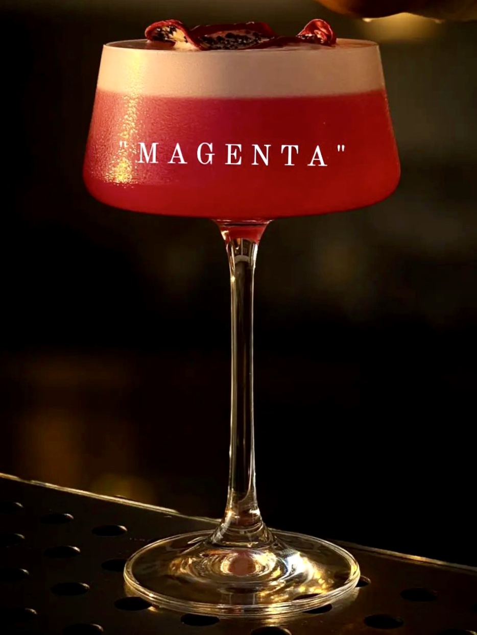 The Magenta signature cocktail in a coupe with pomegranate garnish