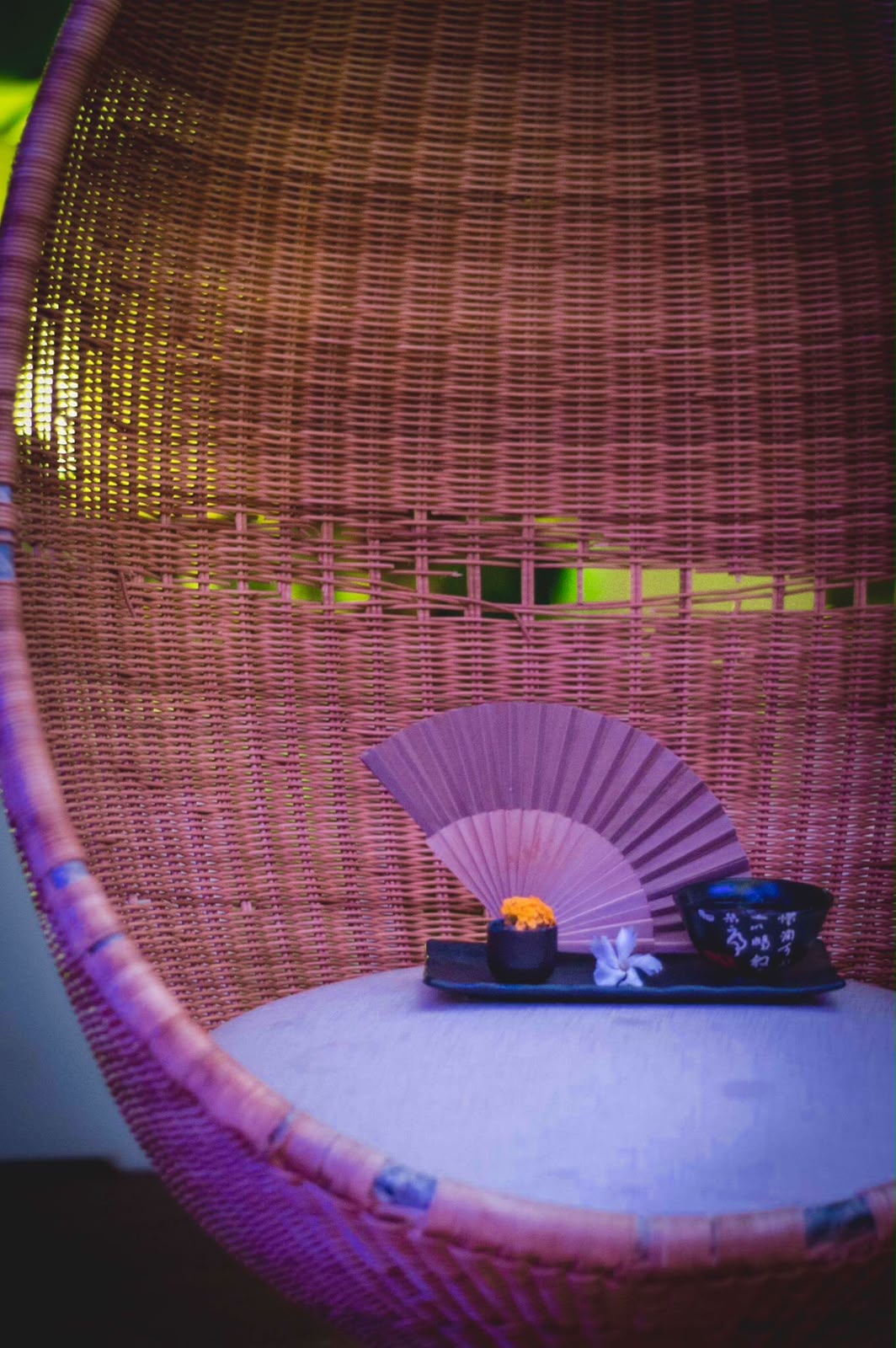 Woven rattan chair with a small tray, paper fan and ceramic bowls