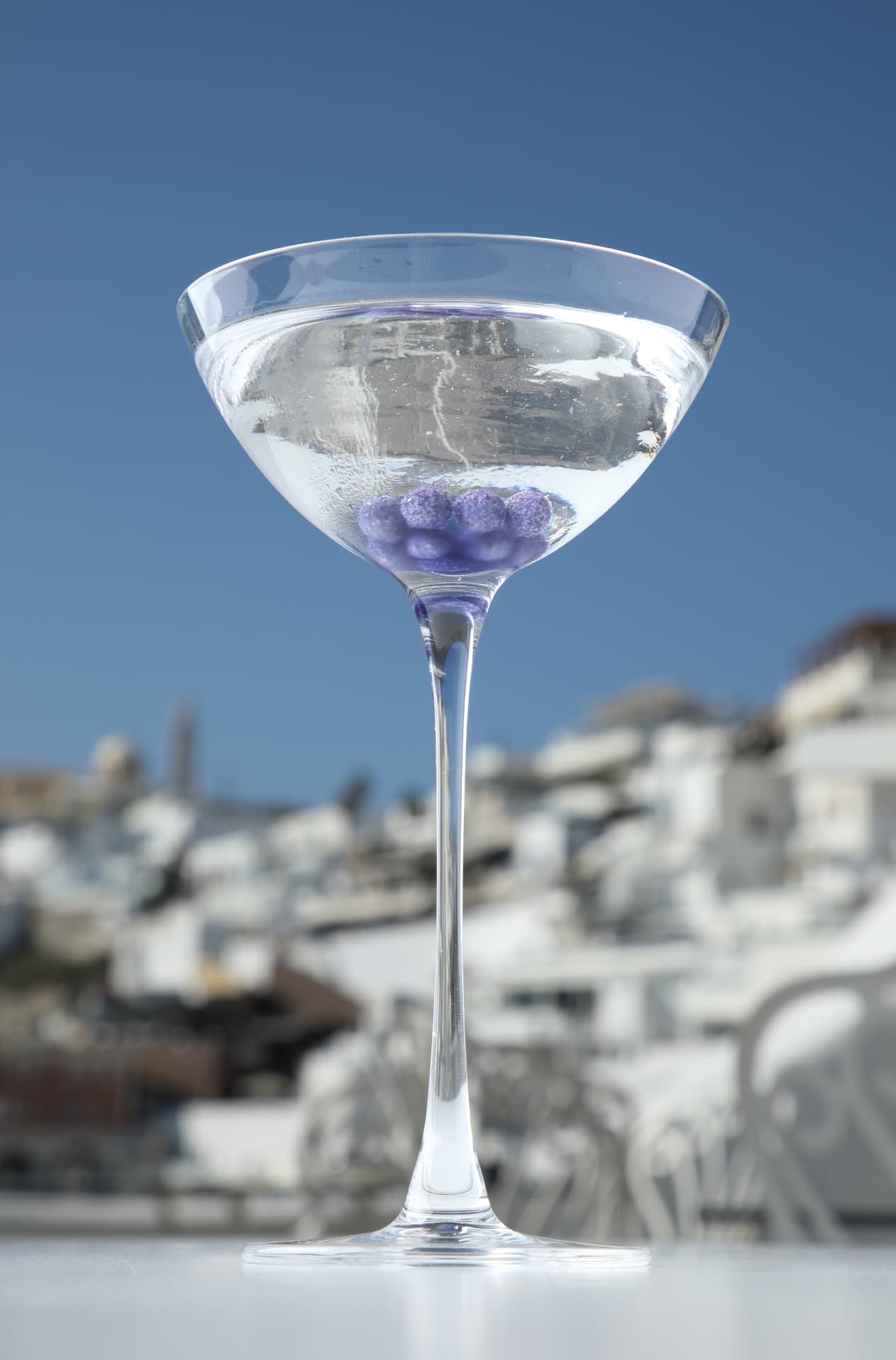 Crystal-clear martini with violet pearls above the whitewashed village