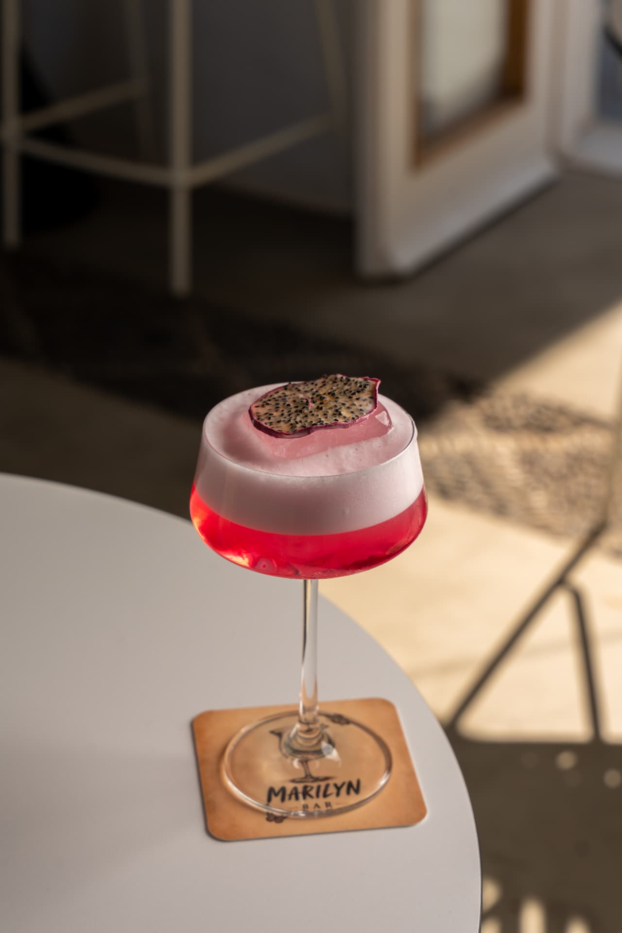 Pink signature sour with dragon fruit garnish on a Marilyn Bar coaster