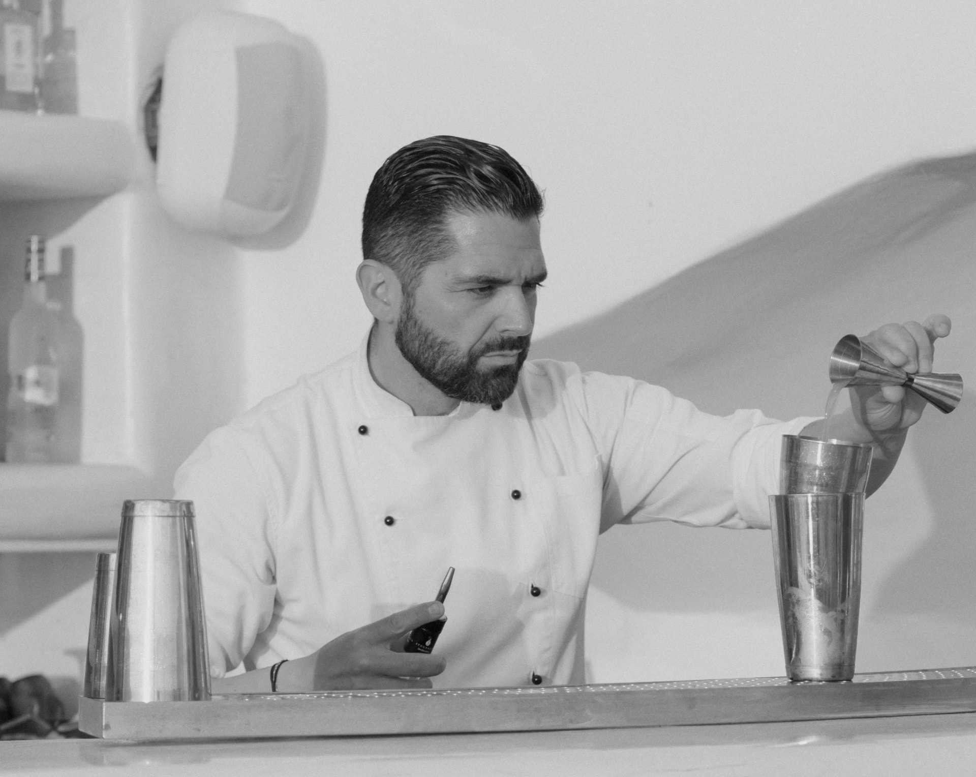Panagiotis Papavramopoulos measuring a pour into a shaker behind the bar